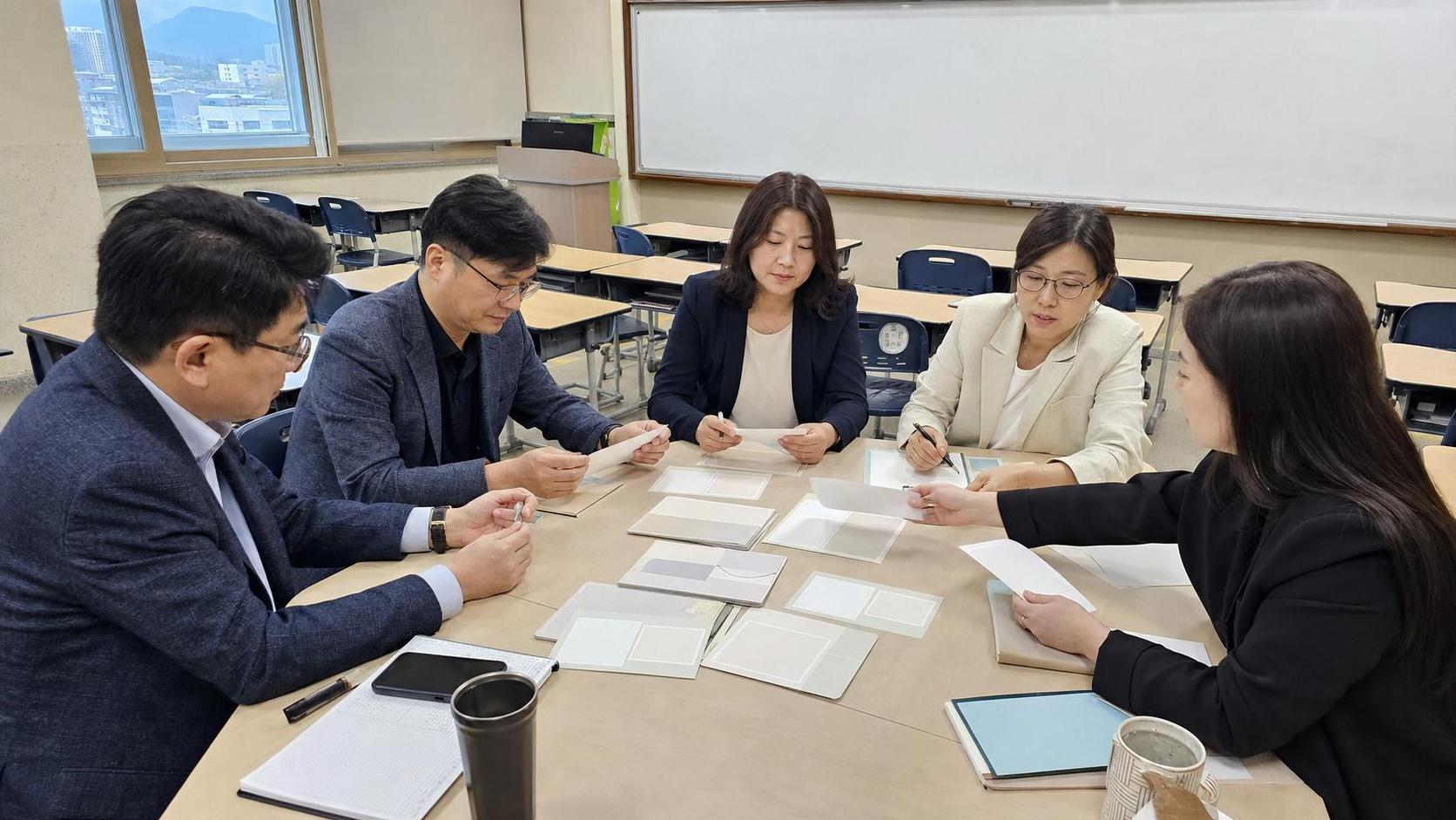한국 교실 회의실에서 학부모 상담 병목 대책을 논의하는 교사와 운영진