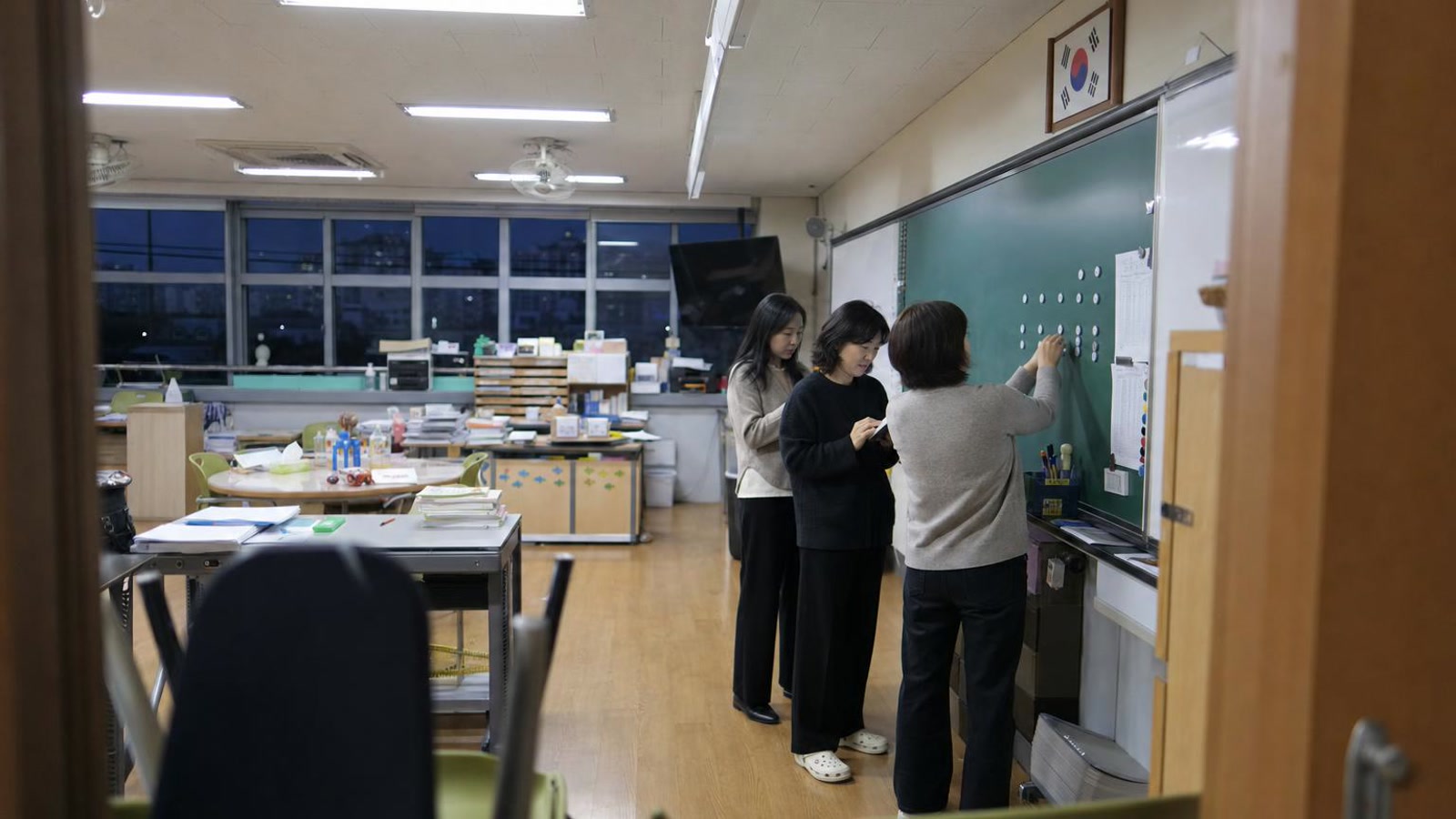 한국 교실형 브리핑 공간에서 교사들이 학부모 상담 후속 회신 상태를 검토하는 실사진형 넓은 장면