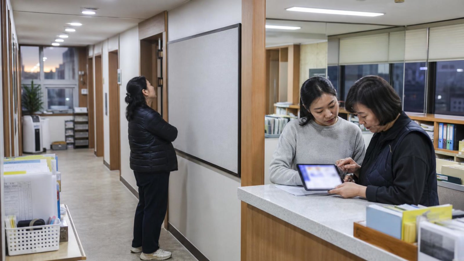 한국 학원 복도와 접수 공간에서 학부모 상담 안내와 예약 상태를 확인하는 실사진형 넓은 장면