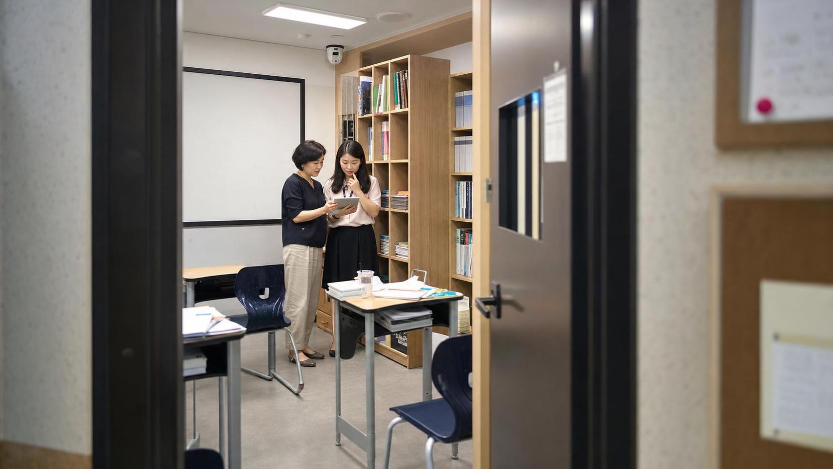 한국 학원 교실에서 상담 후 재점검 일정을 확인하는 교사와 운영자