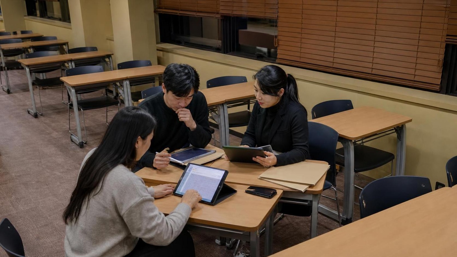 한국 학원 스태프 라운지에서 상담 기록 리포트를 확인하는 교직원들