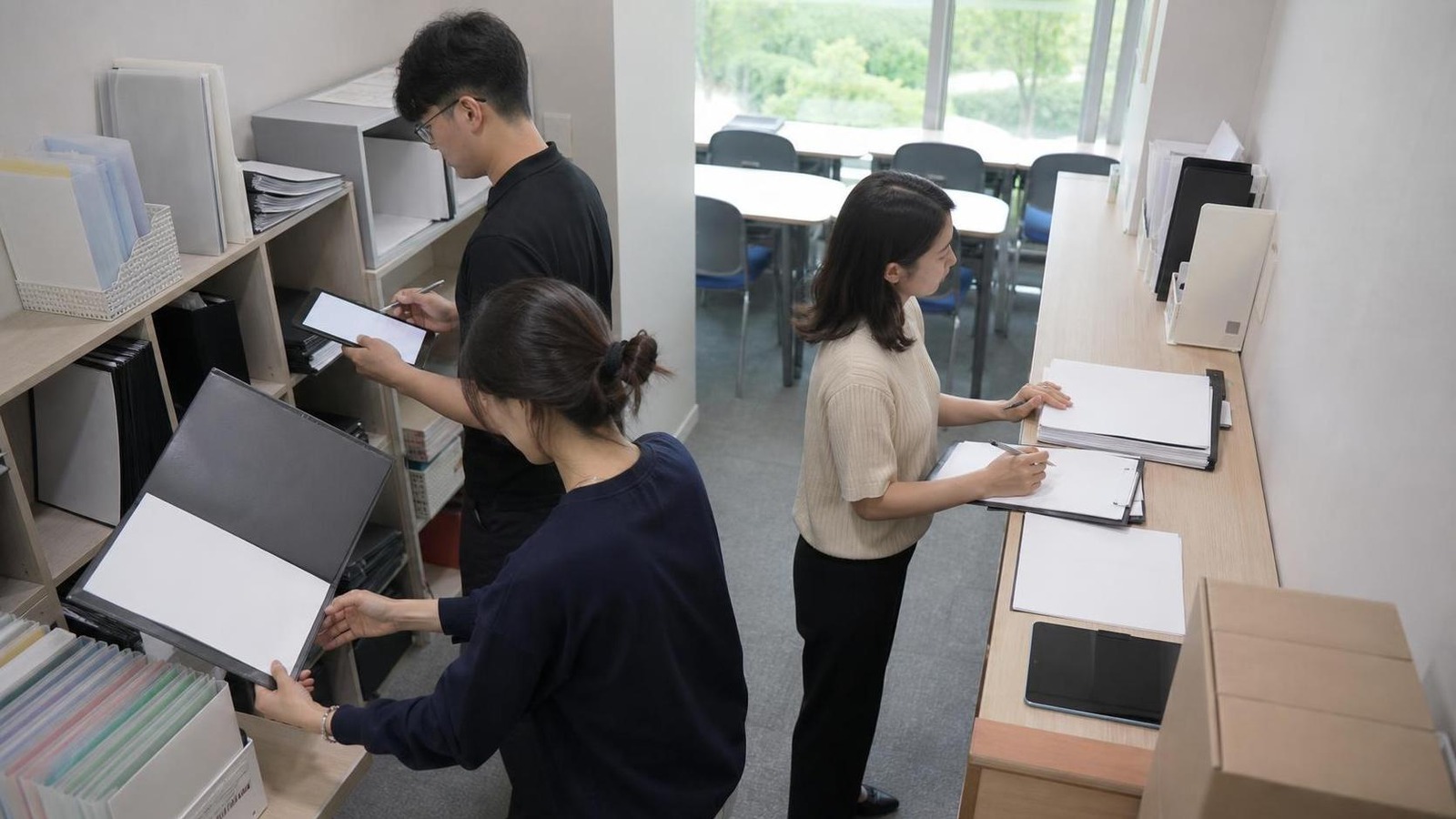 한국 학원 자료실에서 상담 전 출결 보강 강사 코멘트를 확인하는 직원들